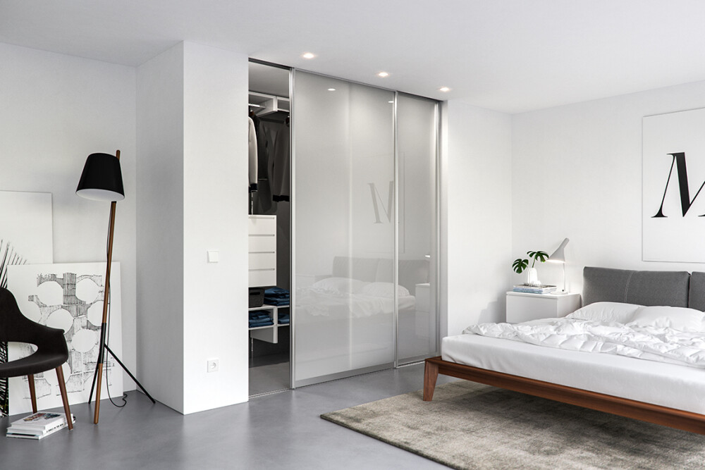Schlafzimmer mit Ankleide unterteilt durch Schiebetüren mit klarem Glas